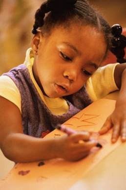 Little girl drawing with crayons on paper