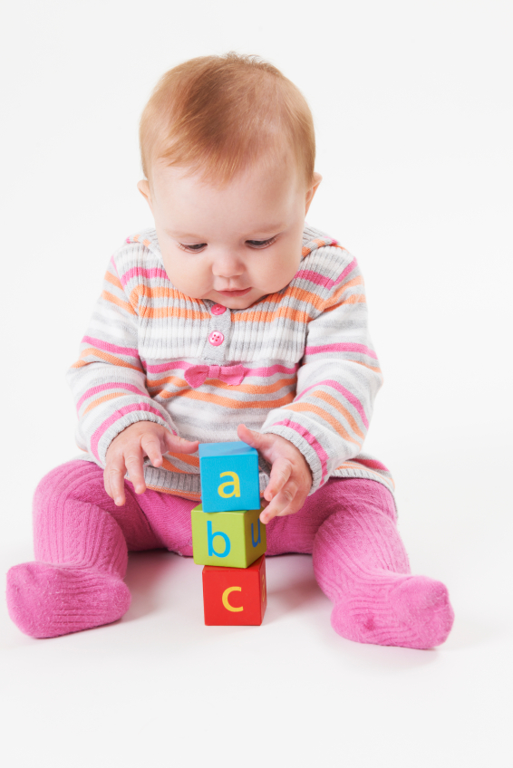 Little girl playing with wooden blocks with letters isolated on white background