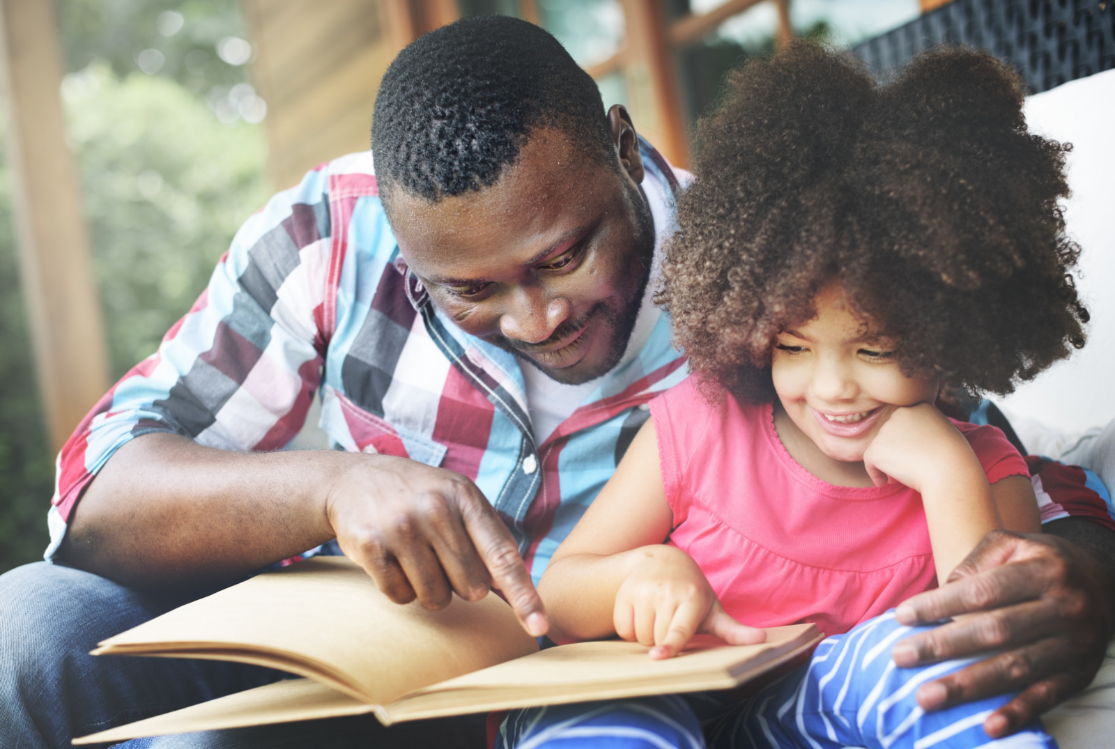 an African American father reading to his young daughter