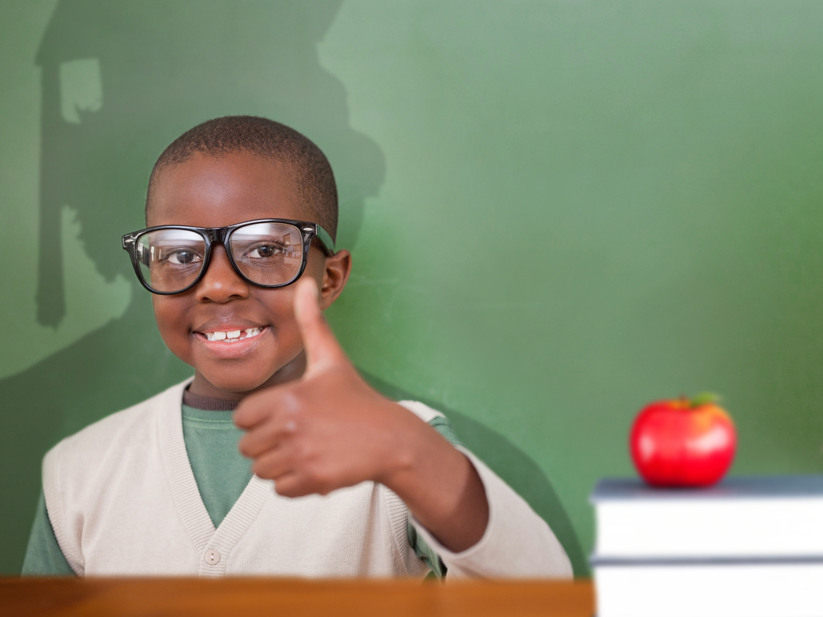 a smiling African American boy doing the thumbs-up gesture